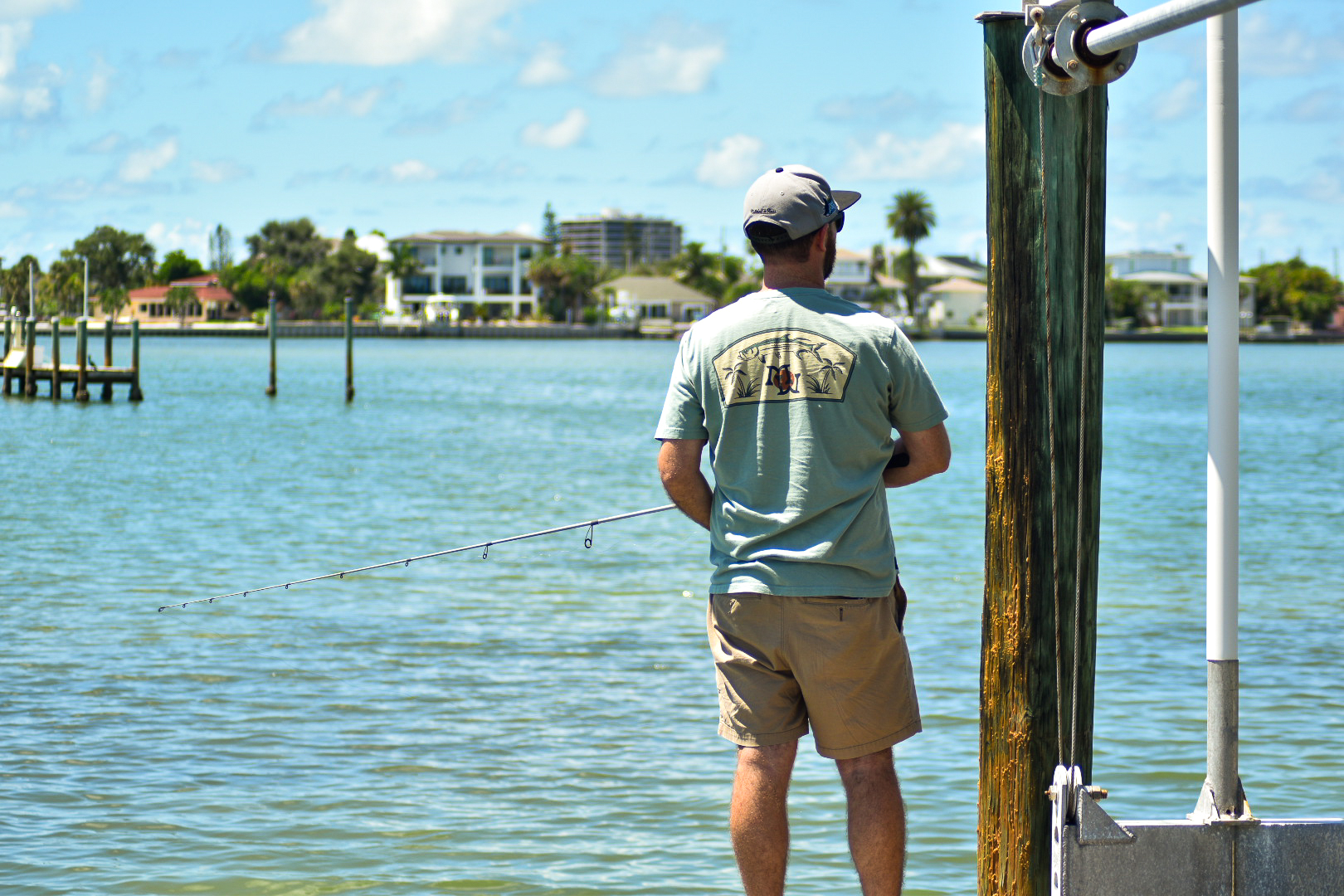 A man fishing off a dock, seen from behind